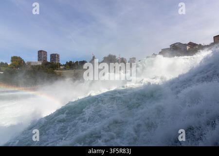 Scenic landscape of a powerful rushing European waterfall with a bright rainbow in the mist, Switherland Stock Photo