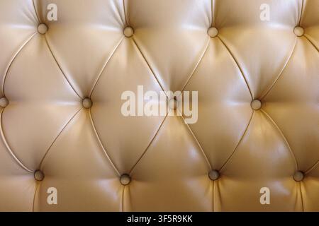 Beige tufted leather upholstery background with buttoned luxury furniture texture. Stock Photo