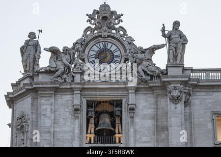 View of the ornate clock and bell tower of St. Peter's Basilica with intricate baroque statues and Roman numerals on the clock face in Rome, Lazio, It Stock Photo