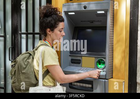 Woman inserting bank card into atm for cash withdrawal Stock Photo