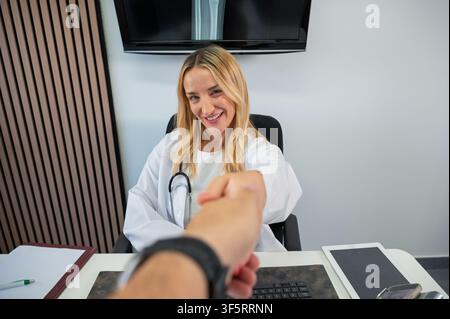 Female doctor offering a handshake to a patient, building trust in a medical consultation Stock Photo