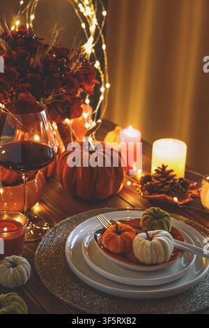 A beautifully decorated table for Thanksgiving or autumn celebration with velvet pumpkins candles and fairy lights creating a warm cozy atmosphere. In Stock Photo