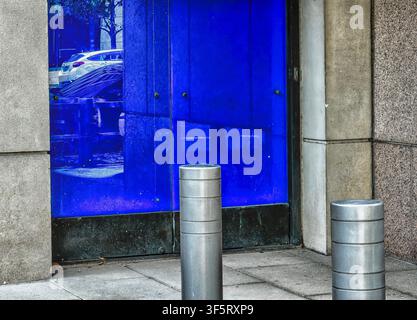 A BIPA Bollard D100, a cylindrical security post in front of a closed blue sliding door Stock Photo