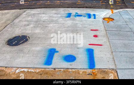 These spray-painted marks on the pavement are used to identify underground utilities before construction or maintenance. Stock Photo