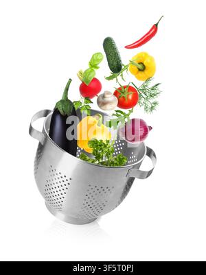 Fresh vegetables and colander in air on white background Stock Photo