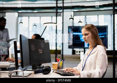 Female engineer in startup office struggling to fix application errors while coding. Young IT professional dealing with computer bugs while coding in software development agency Stock Photo