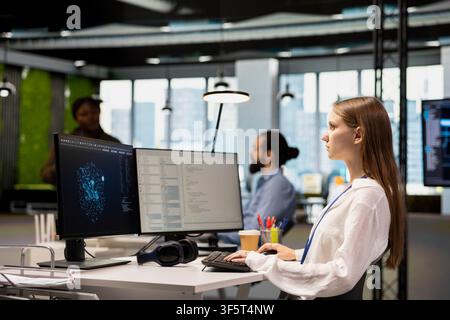 Junior programmer using machine learning AI LLM chatbot, optimizing company systems performance. Young female engineer using artificial intelligence assistant to automate scripts Stock Photo