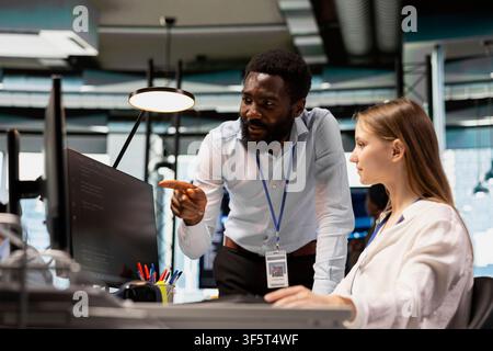 Engineers working together reviewing code snippets in modern workspace, adjusting configurations. IT staff members cooperating, running diagnostic tools, monitoring API cloud services Stock Photo