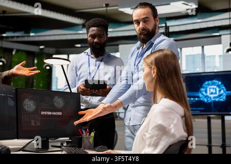 Anxious team of software developers analyzing hacker warning popup, working on countermeasures. Tense tech startup teamworking colleagues responding to data breach alert on screen Stock Photo