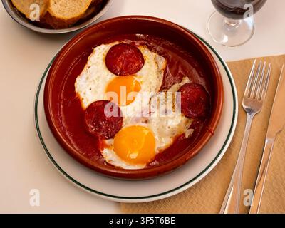 Fried eggs with chorizo and tomato paste in pan close up Stock Photo