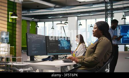 Female admin using AI neural networks tech on computer to optimize performance and forecast issues. Woman in office training artificial intelligence deep learning models using PC, camera A Stock Photo