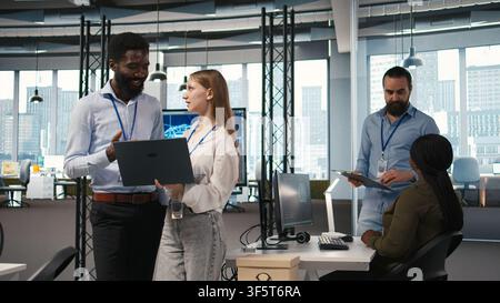 Female engineer and coworker coding AI algorithms to debug software issues and improving system stability. Young woman and colleague in tech startup office configuring settings using device, camera A Stock Photo
