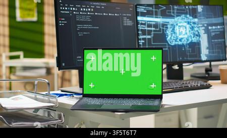 Green screen laptop and AI algorithms running on computer monitors in empty startup workspace deploying machine learning models. Mockup notebook and artificial intelligence coding platform in office Stock Photo