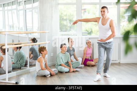 Teen visitors to choreographic class, observe professional rendering of dance performances couch Stock Photo