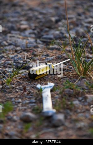 A small wrench and a Phillips screwdriver resting on gravel dirt ground at sunset in the Amazon Rainforest Stock Photo
