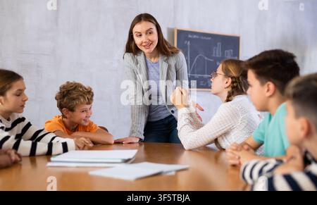 Teacher talking to group of preteen schoolchildren in classroom Stock Photo
