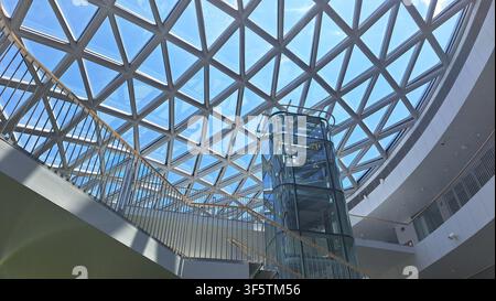 Modern geometric glass roof structure with steel frame design, skylight canopy reflecting clear blue sky with bright sunlight, futuristic architectura Stock Photo