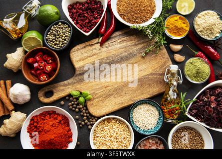 Various spices in a bowls and empty cutting board on black concrete background. Top view copy space. Stock Photo
