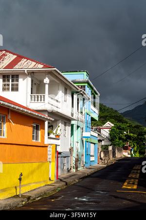 Colorful traditional Caribbean architecture along a street in Roseau, Dominica under a dark stormy sky. Stock Photo