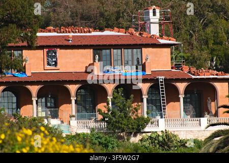 Mediterranean style hillside home under renovation at Torrance Beach, California, featuring scaffolding, clay roof tiles, and arches. Stock Photo