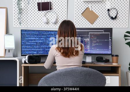 Female programmer coding on a desktop computer with multiple screens, Software development and IT career Stock Photo