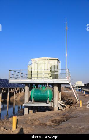 The image shows box-type substation facilities in a solar power plant. The white box body and radiators on both sides are installed on an elevated pla Stock Photo