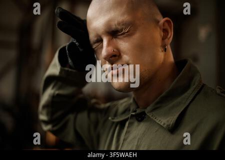 Tired Male Welder Wiping Sweat from Forehead in Metal Workshop Stock Photo