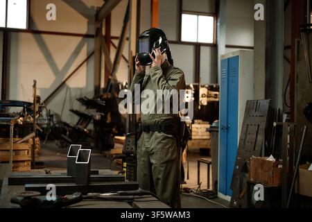 Male Welder Putting on Protective Helmet in Industrial Workshop Stock Photo