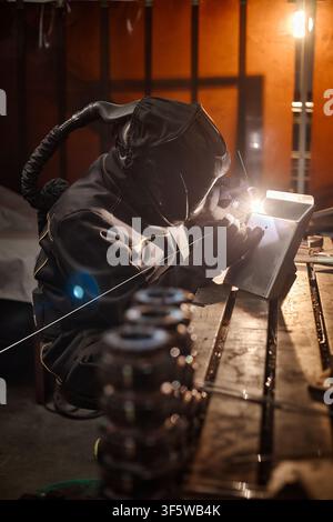 Professional Welder in Protective Gear Working on Metal in Workshop Stock Photo