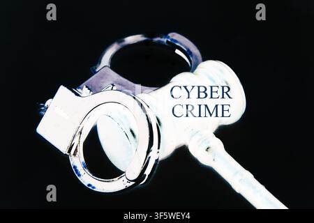 Close-up cinematic concept image of a judge's gavel and metallic handcuffs with the words "Cyber Crime" integrated into the composition. The objects s Stock Photo