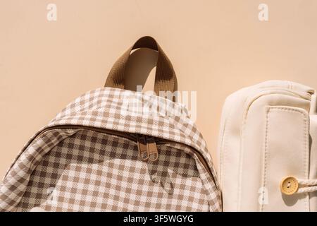Checkered backpack and beige pencil case in warm sunlight, stylish back to school concept Stock Photo