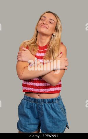 Woman embracing herself with a warm smile, showing self-care and positivity Stock Photo
