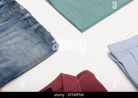 Close-up of folded jeans, knitwear and shirts on a white surface photographed in Nottingham, England, United Kingdom on 8 June 2015. Stock Photo