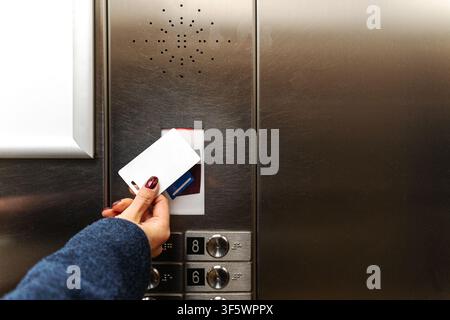Woman using access card on metal control panel with red sensor light Stock Photo