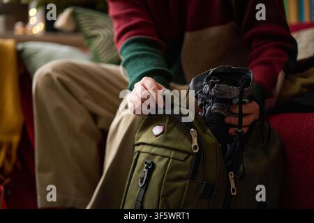 Cropped shot of Caucasian young adult packing travel gear into green backpack, preparing for outdoor adventure. Image ideal for tourism marketing and retail promotions, close up Stock Photo