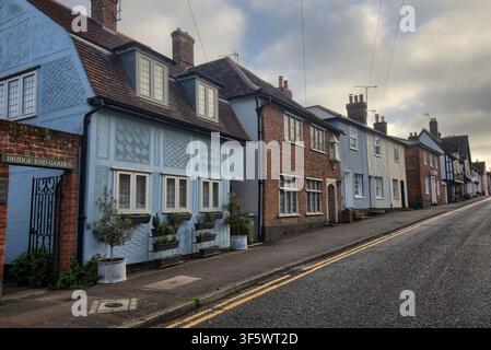 Historic timber-framed and colorful plastered cottages with decorative pargeting lining a sloping Castle Street hill in Saffron Walden, Essex. Stock Photo