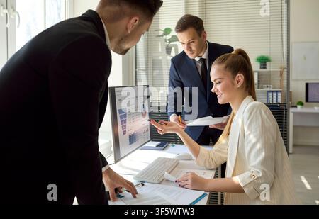 Business team reviewing analytics and finance dashboard on computer in office Stock Photo