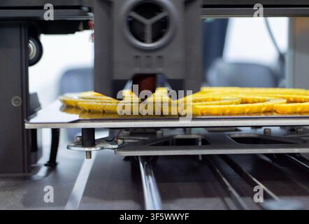 Process printing on 3D printer. The 3D printing process from molten plastic yellow color. 3D printing technology. FDM technologies. Fused Deposition Modeling. Additive manufacturing. Stock Photo