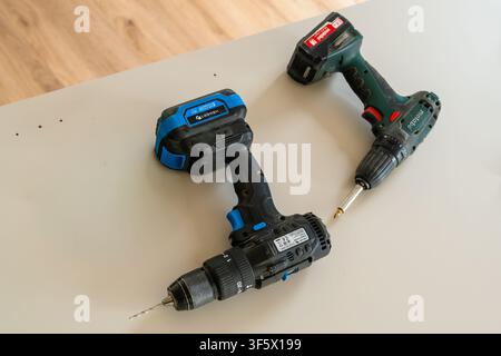 PRAGUE, CZECH REPUBLIC, JUNE 2026. Using two cordless drills equipped with drill and screwdriver bits on a work surface. Tools displayed in a well-lit environment, showcasing precision engineering and functionality.  Stock Photo