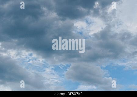 Dark storm clouds gather in the bright blue sky, creating a sense of atmospheric drama and impending weather shifts. Stock Photo