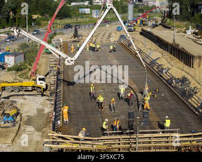 Aerial view of construction workers pouring concrete for a new road viaduct using pump trucks in Wieliczka, Lesser Poland Voivode, Poland. Stock Photo