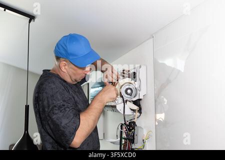 Technician repairing wall mounted air conditioner. Professional maintenance of cooling system. Indoor Stock Photo
