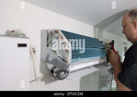 Technician repairing air conditioning unit in bright room. Specialist performing maintenance on hvac system Stock Photo