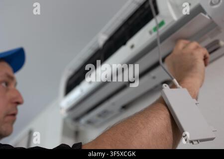 Technician checking air conditioner unit. Repairman installing cooling system equipment at home Stock Photo