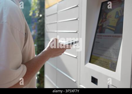 Young man with backpack using outdoor automated parcel locker station Stock Photo