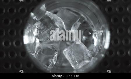 Ice cubes inside a glass on a bar mat, top view, capturing the refreshing essence of a cold drink Stock Photo