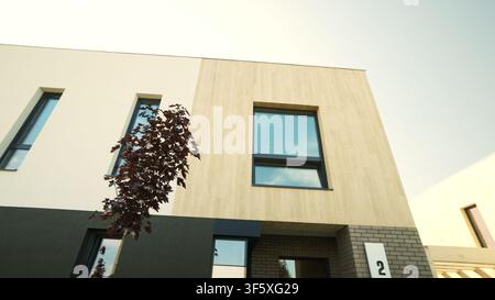 Modern townhouse exterior featuring minimalist architecture, contemporary design elements, and a small tree against a clear sky Stock Photo