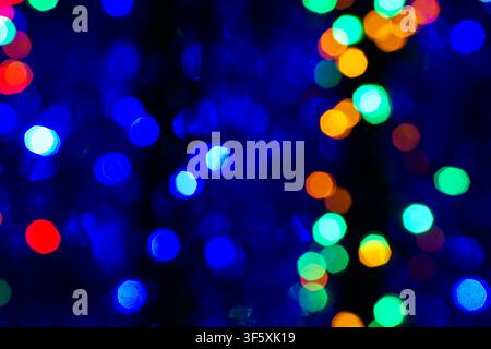 Abstract blured background of dark multi colored shiny Christmas tree decorations at night Stock Photo