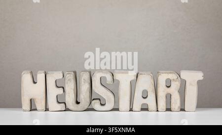 Restart Idea From German Word NEUSTART Shown With Minimal Concrete Typography On Neutral Background Stock Photo