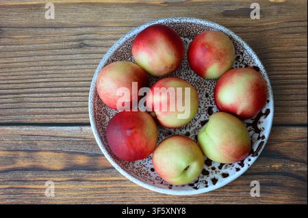 Fresh Nectarines in Bowl on Wooden Table flat lay copy space Stock Photo